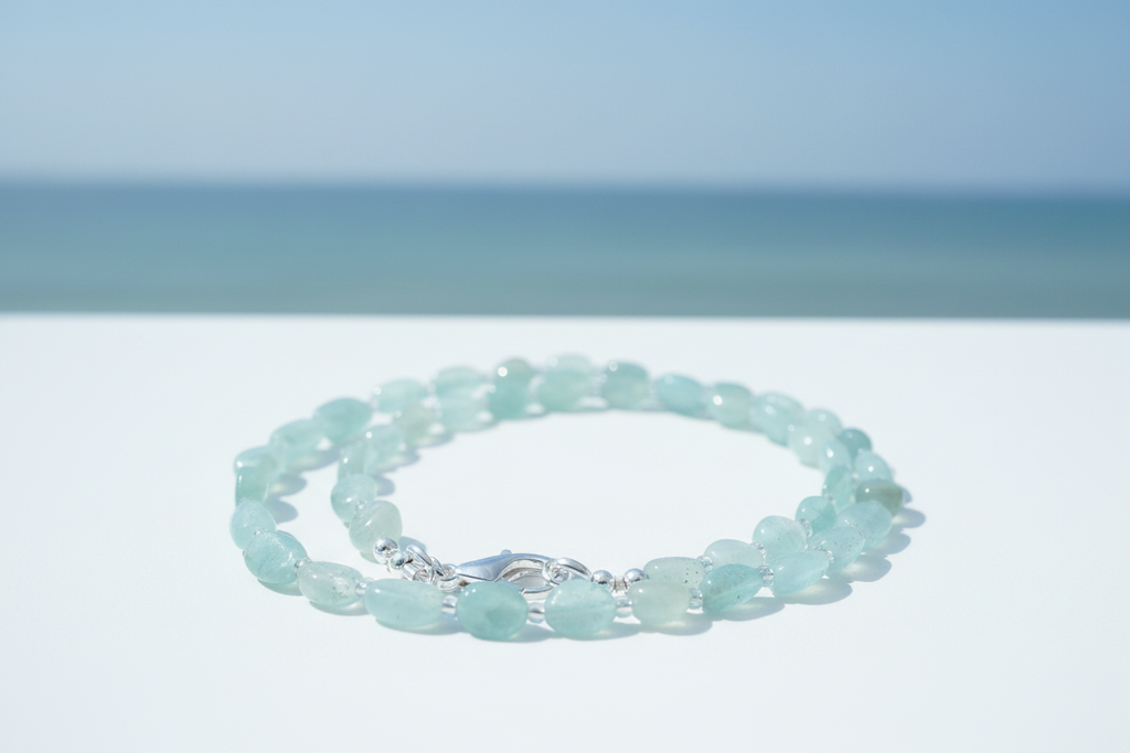 Pale aquamarine tumbled bead necklace with silver spacers and silver lobster clasp on coastal background