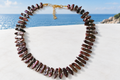 Cultured freshwater stick pearl necklace with seed pearls and gold plated lobster clasp on a white surface with coastal sea view