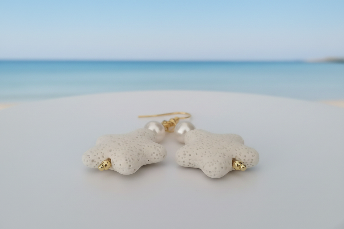 White lava stone starfish and freshwater pearl drop earrings on coastal background